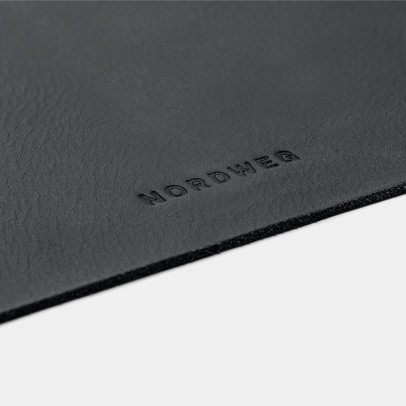 Close-up of black Workplace leather desk pad edge with Nordweg logo