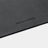 Close-up of black Workplace leather desk pad edge with Nordweg logo