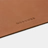 Close-up of caramel Workplace leather desk pad edge with Nordweg logo