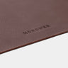 Close-up of coffee Workplace leather desk pad edge with Nordweg logo