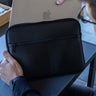 Nordweg Workplace leather laptop sleeve case in Black with laptop being placed behind the front zip pocket