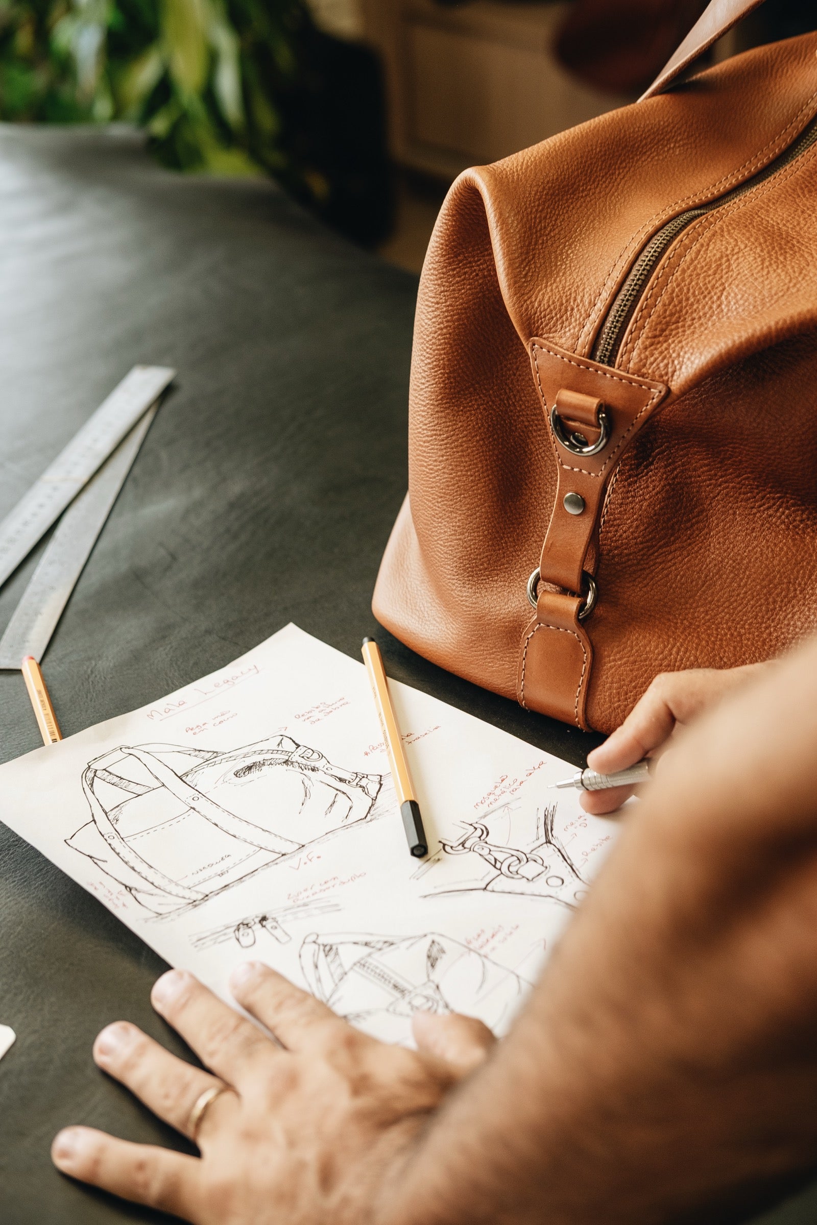 Legacy leather duffel beside design sketches in the workshop