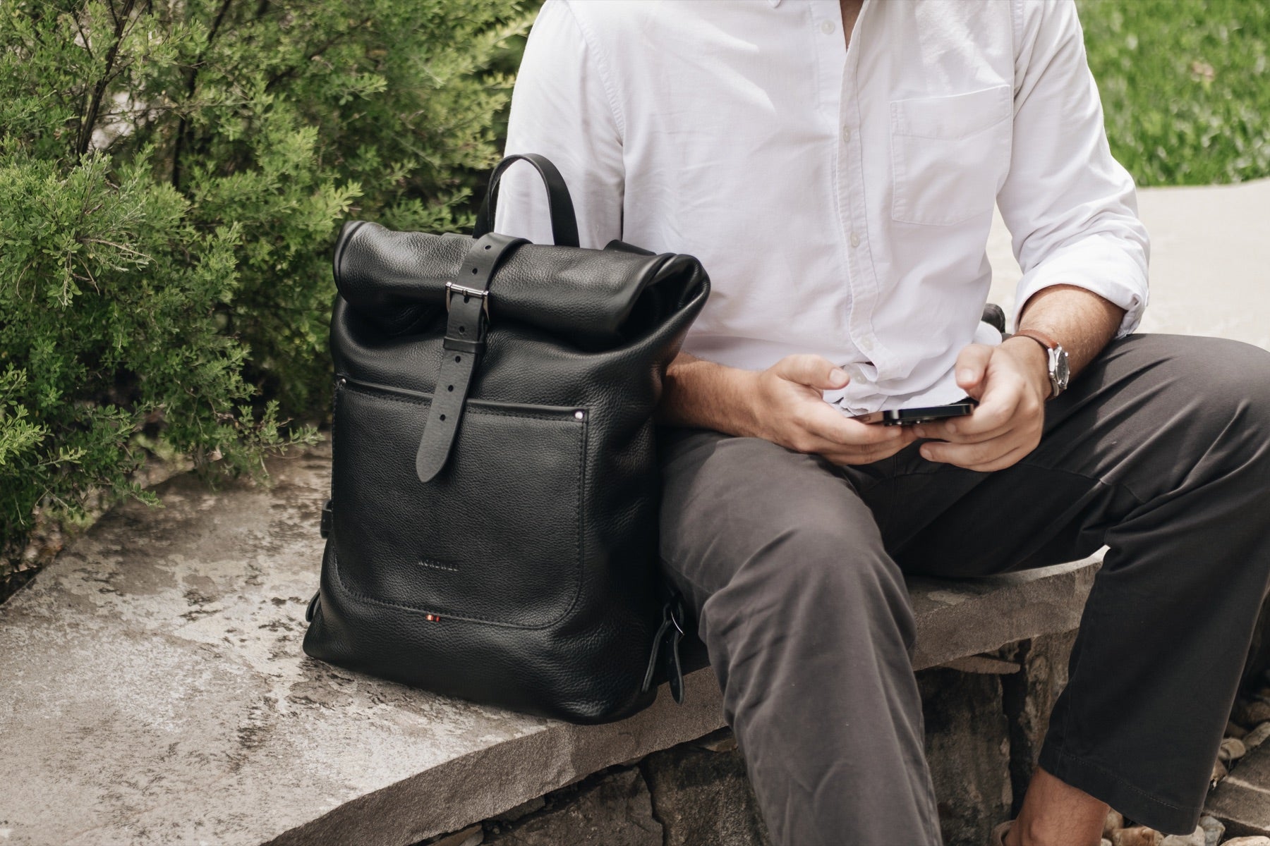 Black Legacy backpack beside a seated customer outdoors
