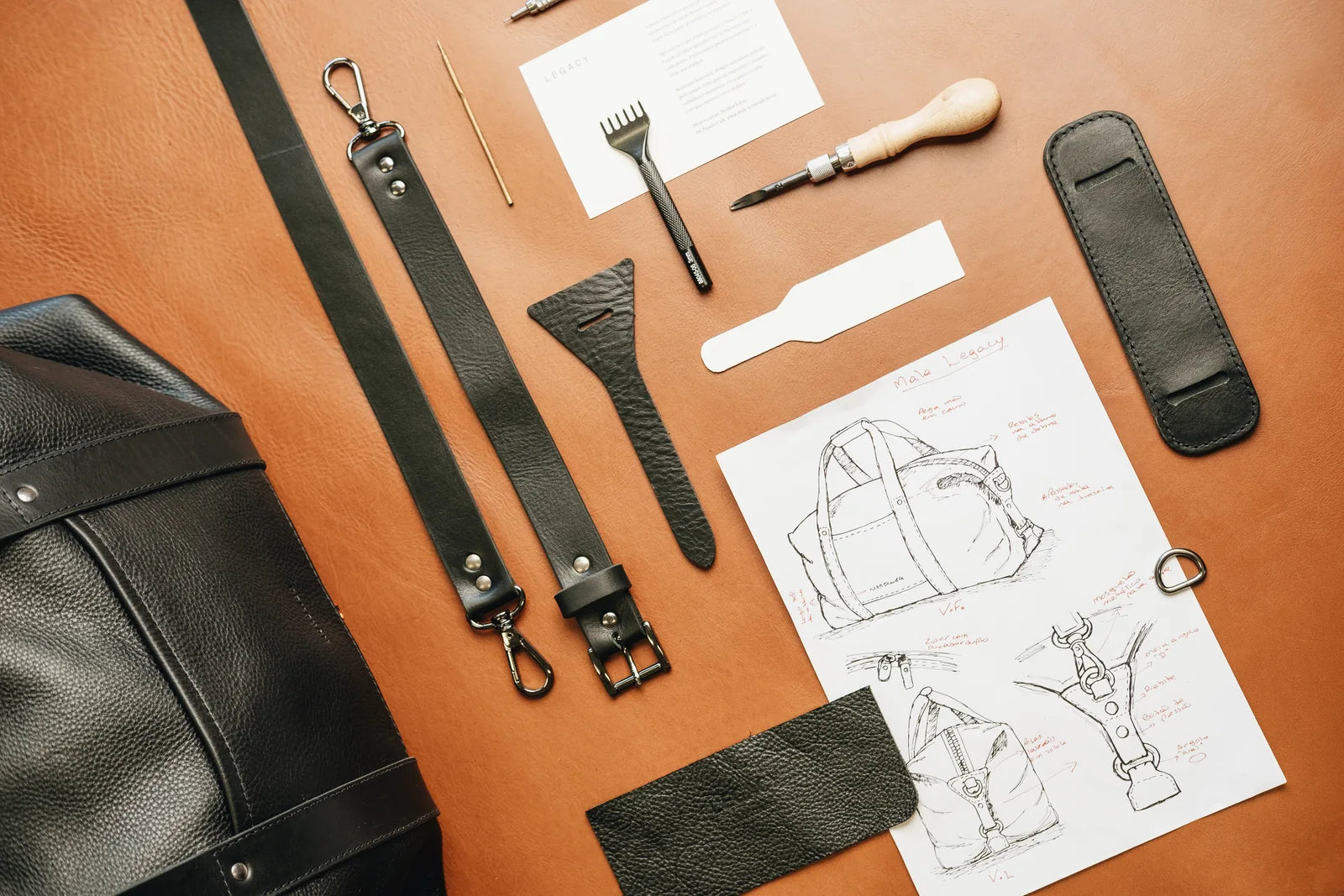Black leather components, tools and a bag drawing arranged on the workbench