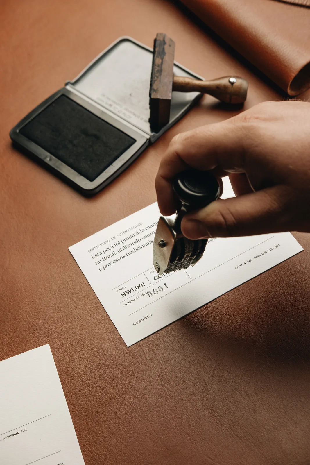A maker stamping a Legacy certificate at the workshop table