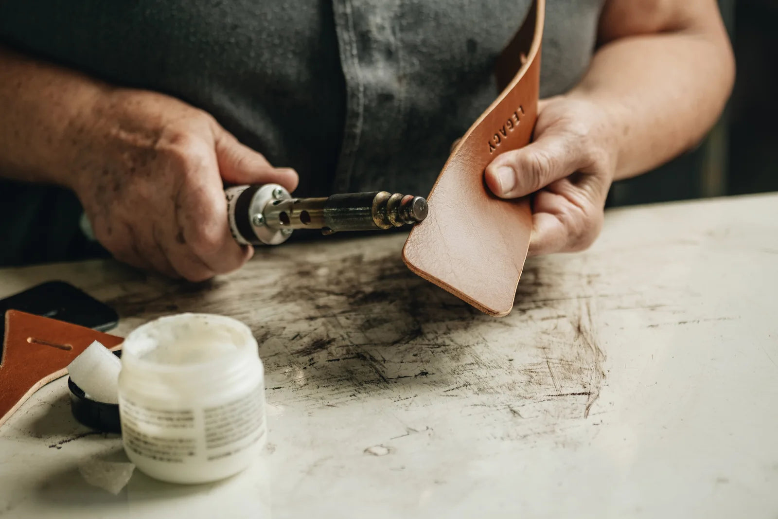 A maker applying finish to the edge of a leather component