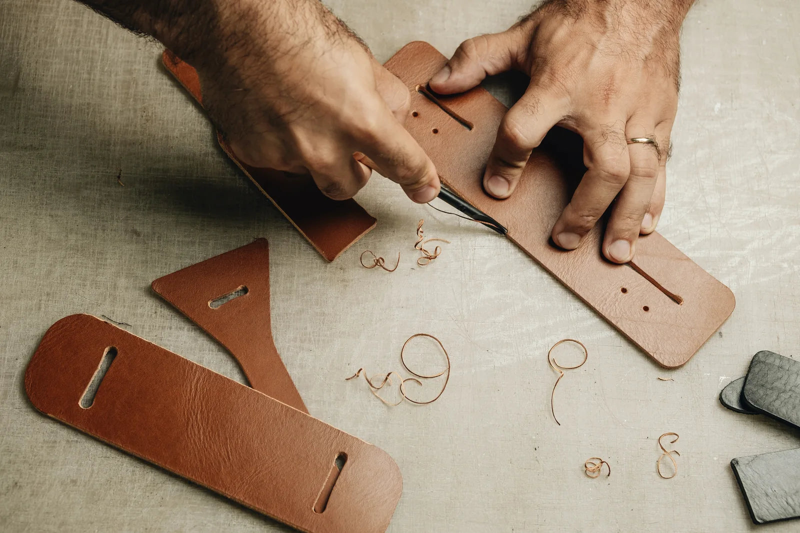 Hands applying adhesive along the edge of a cut leather component