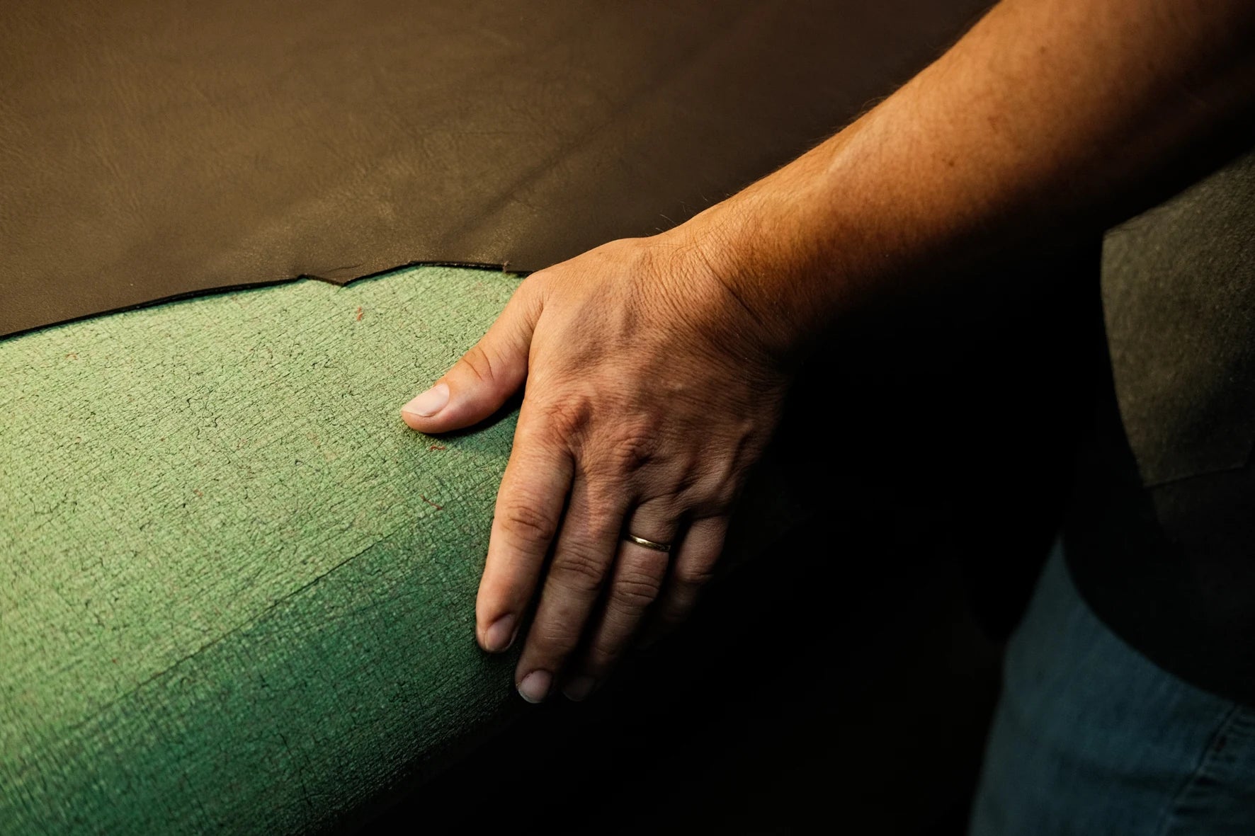 Hands working leather on a cutting table in the Nordweg workshop