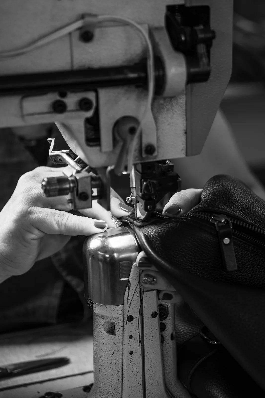 A maker guiding a leather piece through a sewing machine