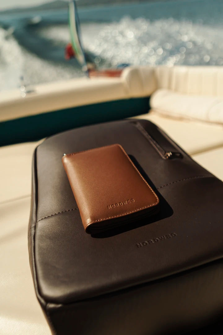 Caramel Nomad passport wallet on a Coffee Nomad backpack on a boat
