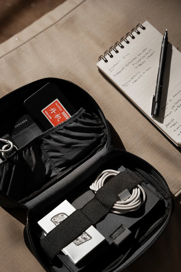 Black Workplace tech organizer open with cables beside a notebook