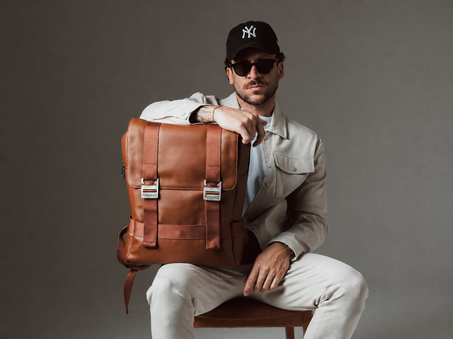 Man holding a caramel Dolomites leather backpack in the studio