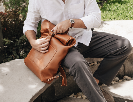 Hands adjusting a caramel Nordweg Legacy leather bag
