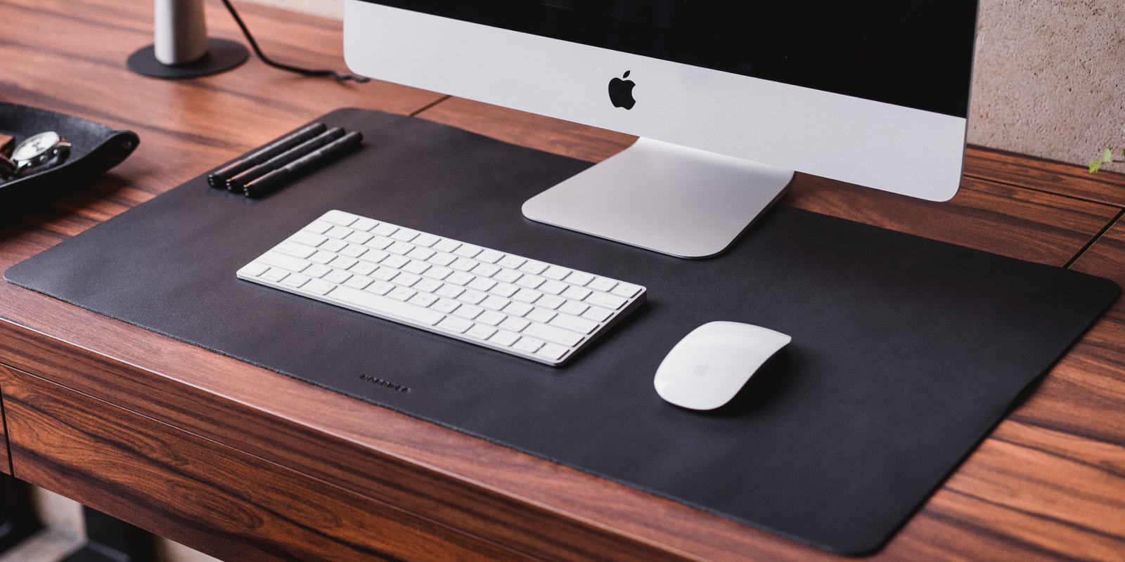 Black Workplace leather desk pad with iMac, keyboard, and mouse